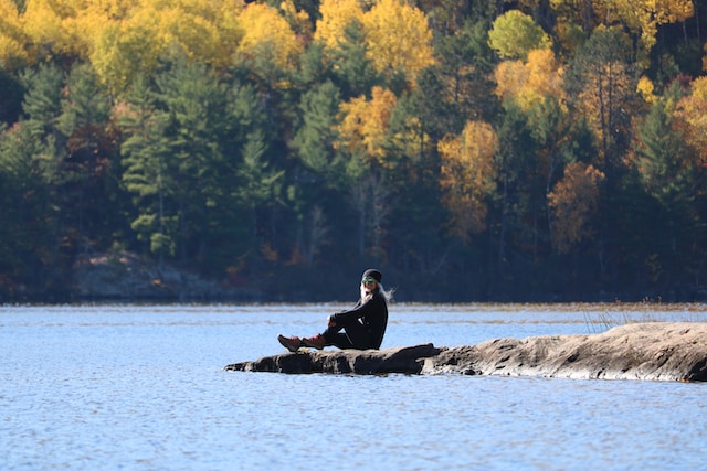 Woman finding peace by sitting on rocks extending to a lake